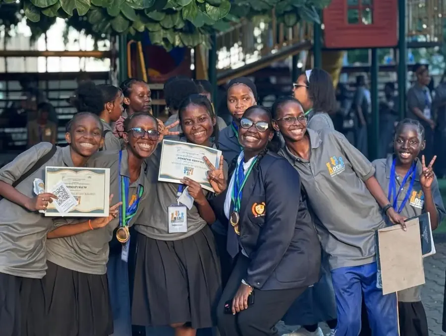 Alpha Girls debate team celebrating with medals and certificates